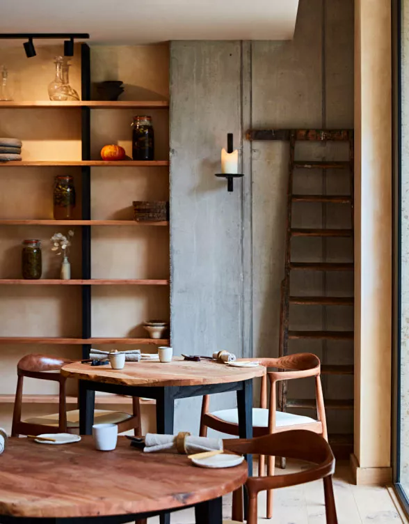 The interior of restaurant St. Barts, wooden tables laid for services in a room with natural tones and ceramics ad jars line the shelves.